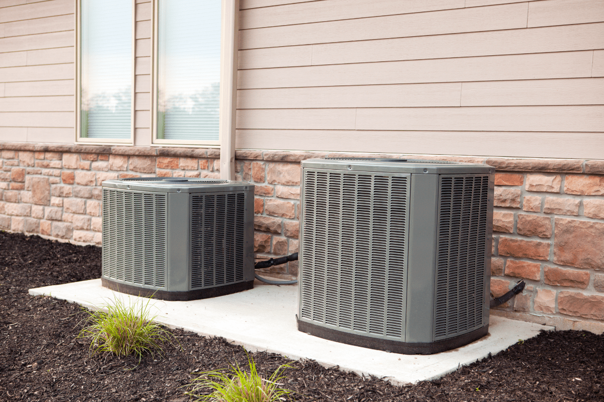 Two outdoor air conditioning units by house.