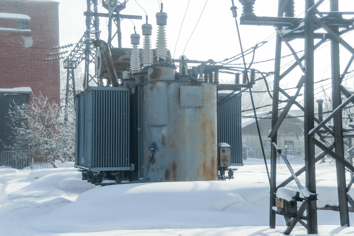 Electrical transformer surrounded by snow.